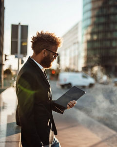Mature businessman using digital tablet on footpath during sunny day