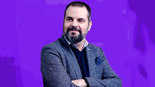 Bearded man in suit with arms crossed