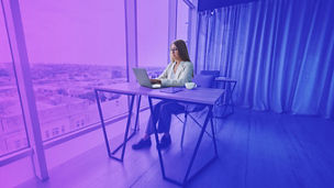 Manager focused woman in casual wear and eyeglasses typing on netbook while working on new project sitting at table in modern workspace