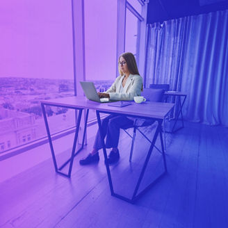 Manager focused woman in casual wear and eyeglasses typing on netbook while working on new project sitting at table in modern workspace