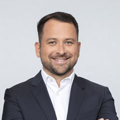 Porträt von Maximilian Mann vor einer hellgrauen Wand