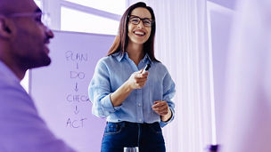 Happy business woman discussing ideas with her team during a meeting. Young business woman giving a presentation in an office.