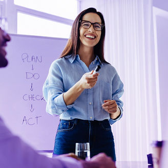 Happy business woman discussing ideas with her team during a meeting. Young business woman giving a presentation in an office.