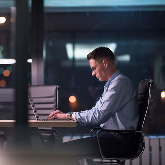 Young man working on laptop at night in dark office. The designer works in the later time.