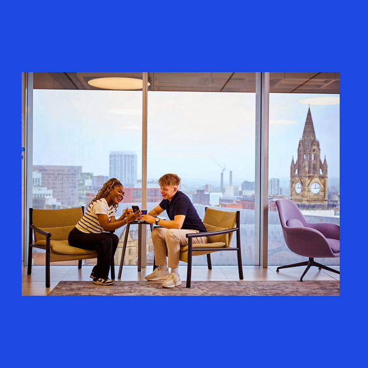 Two people seated across a small table in an office lounge.