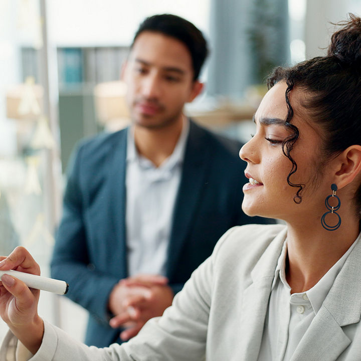 Two people collaborating at a transparent board in an office
