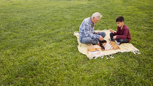 Older Hispanic man and grandson playing chess in park. Keywords: Chess, Child, Grandfather, Senior Adult, Elevated View, Grass, Childhood, Competition, Latin American and Hispanic, Full Length, Outdoors, 70-79 Years, Copy Space, Adult, Bonding, Grandson, Multi-Generation Family, Sitting, Togetherness, Chess Piece, Cross-legged, Males, Retirement, Leisure Games, Men, 6-7 Years, Active Seniors, Affectionate, Blanket, Boys, Brown Hair, California, City Of Los Angeles, Colour Image, Day, Enjoyment, Horizontal, Leisure Activity, Lifestyles, Looking Down, Love, Nature, People, Photography, Primary Age Child, Senior Men, The Ageing Process, Two People, USA, Weekend Activities 