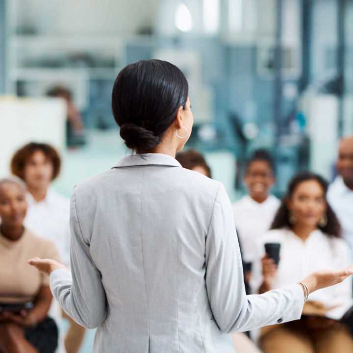 Person talking to a group of people within an open plan indoor space