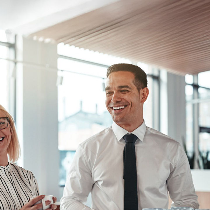 Colleagues laughing whilst stood in an indoor office space