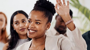 Woman with her hand up during a presentation