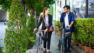 Colleagues walking to work pushing their bicycles
