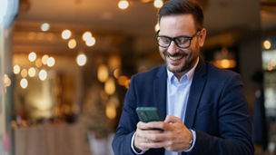 Smiling Businessman Texting on Smartphone in Cafe