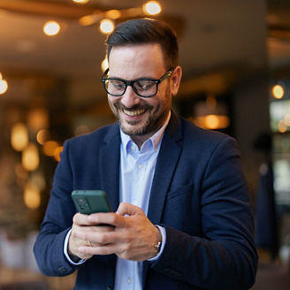 Smiling Businessman Texting on Smartphone in Cafe