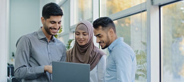 Multiethnic colleagues listens Arabic team leader explain corporate task application to diverse workers indian businesspeople looking on laptop screen working together, teamwork brainstorm concept. High quality photo