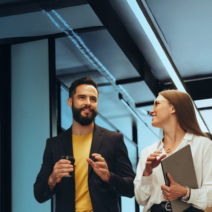 Two people in conversation sat at a table with a laptop