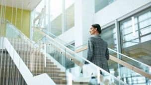 Female Worker On Stairs In Office Indoors. Business Woman In Modern Office Building. High Resolution