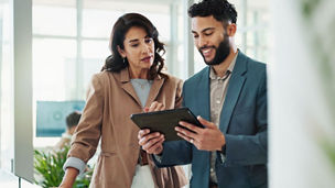 female mentoring a male colleague, man holding a tablet