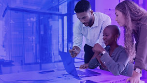 A group of people looking at a laptop on a table in an office