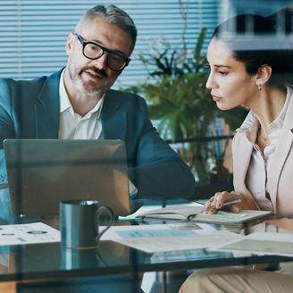 People looking at a laptop whilst sat at a desk