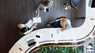 Overhead view of people meeting around a curved desk in an open office