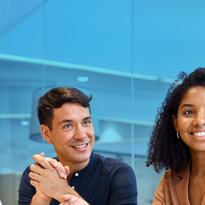 Two people smiling whilst sat at an office table in front of laptop