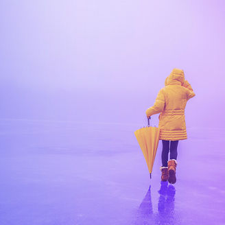 woman in yellow coat walking with yellow umbrella