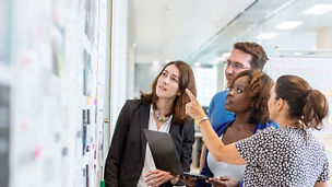 People pointing at a board in an office