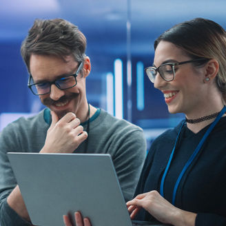 Two colleagues talking and looking at laptop