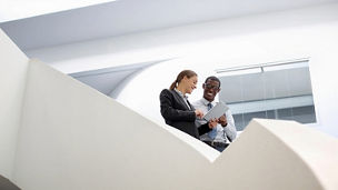 Two people talking in a modern office space with curved architecture