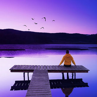 sitzende Person auf Steg an einem See