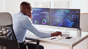 Person seated at a workstation reviewing data on large curved screens