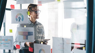 Person presenting data using charts displayed on a glass wall