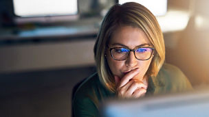 A person with glasses looking at a computer screen