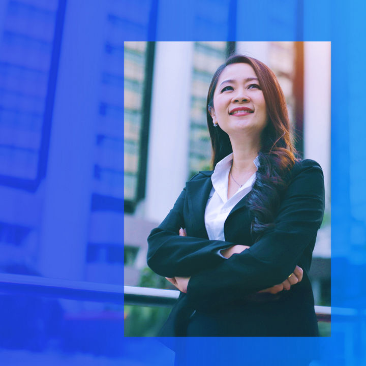 Person in a business suit standing with arms crossed in front of a modern office building