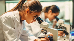 Person in a lab coat using a microscope in a laboratory