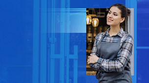 person-in-an-apron-standing-with-arms-crossed-outside-a-shop