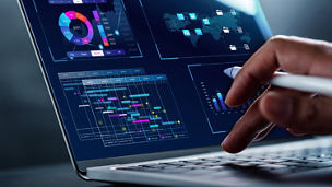 Hands using a laptop displaying charts and data visualisations on the screen