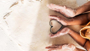 Person making heart shape from sand