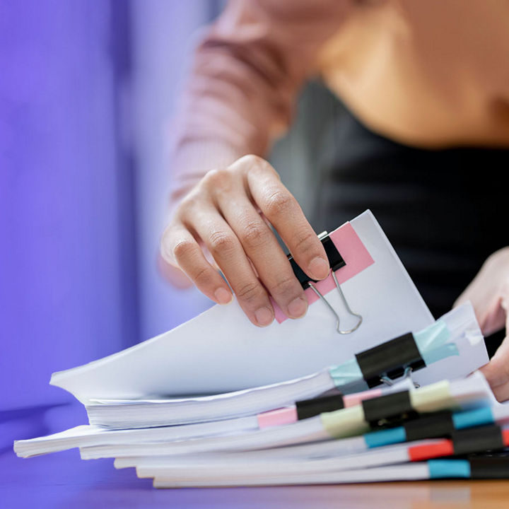 Person organizing stack of clipped documents on a desk
