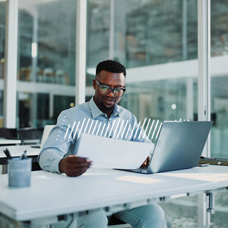 Person reviewing a document and working on a laptop in a modern office.