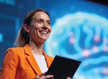 A person stood holding a tablet in front of a large digital screen showing a digital brain graphic