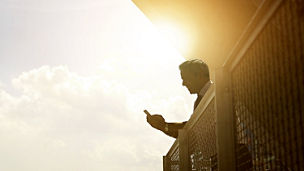 Person standing in the balcony looking at his phone