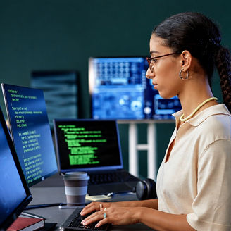 A person uses multiple computer screens at an office workstation.