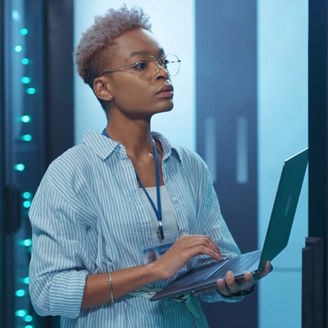 Person using a laptop while standing in a data center.