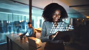 Person using a tablet in a modern office with a digital data overlay.