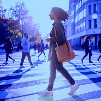 Person walking across a city crosswalk with others in the background