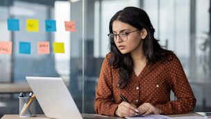 Serious thinking and concentrated focused business woman behind paper work inside office. An employee of the company compares the data of the report with documents, an accountant, auditor at work.