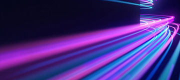 Rastos de luz em tons de rosa, roxo e azul sobre um fundo escuro, criando um efeito de movimento e velocidade com um estilo futurista.