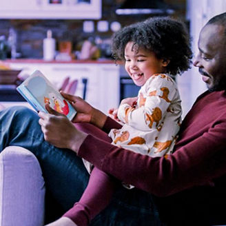 Ojciec i córka czytają książkę dla dzieci w salonie