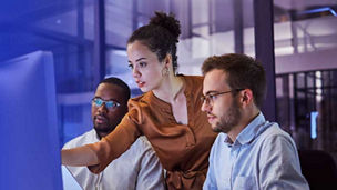 Two man and a woman looking at desktop